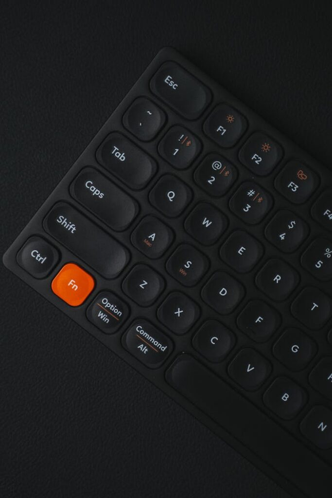 Close-up of a sleek black keyboard with an orange 'Fn' key, highlighting minimalistic design.