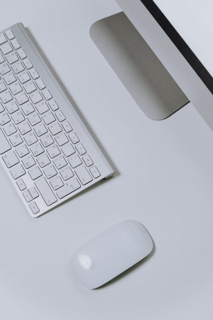 Stylish overhead view of a minimalist Apple workspace featuring a keyboard and mouse on a clean surface.